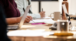 A table during a workshop with pens, paper, laptops and coffee cups