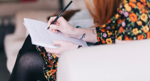 A person writing with pen and paper