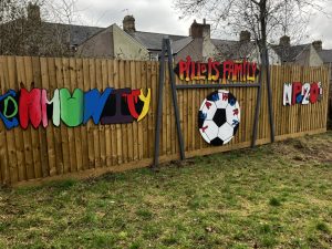A mural on a garden fence, consisting of the words COMMUNITY, PILL IS FAMILY and NP20