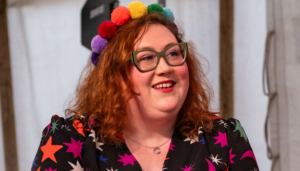 A person in a colourful dress and headband speaking at an event